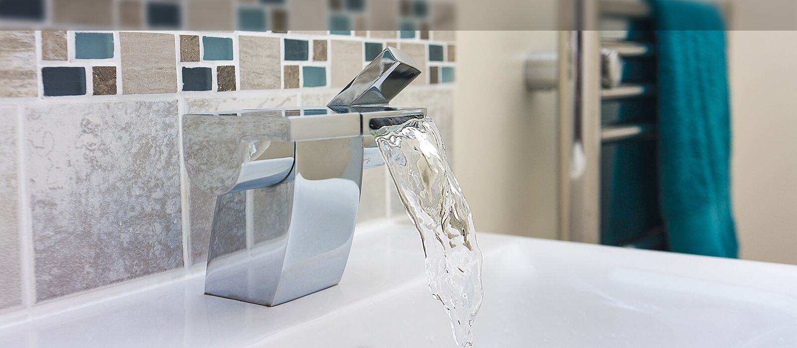 Chrome waterfall tap running into a white basin